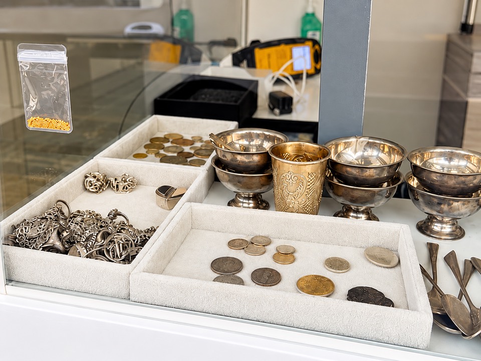 Enhanced view of jewelry, coins, and metalware in the shop display case